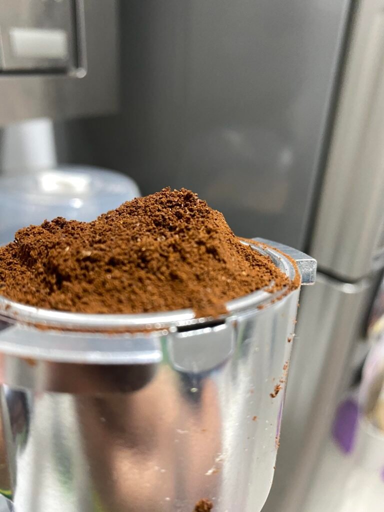 Coffee grounds being dosed into a portafilter basket