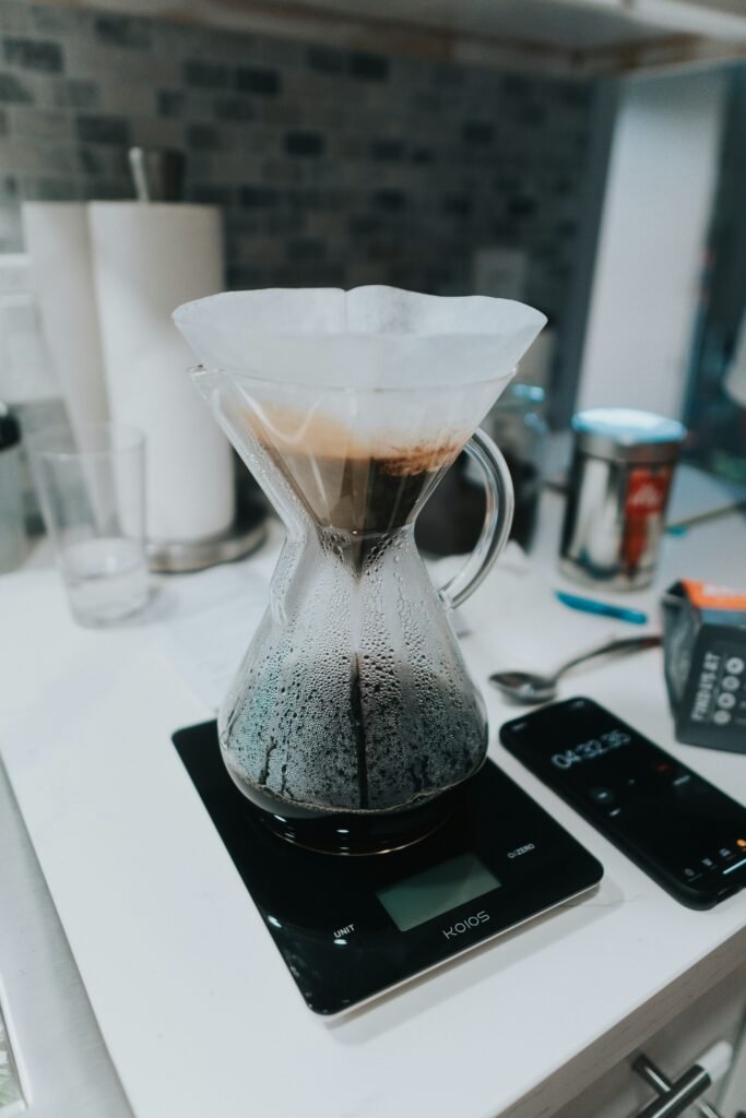 Coffee scale measuring beans, with a pour-over setup in the background