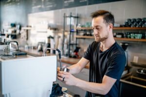 Barista demonstrating professional latte art pouring technique with microfoam milk