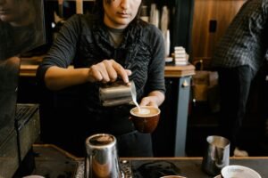 Barista creating heart-shaped latte art with steamed milk and espresso