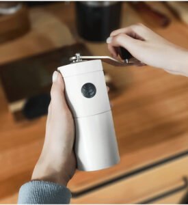 A person using a manual coffee grinder to grind fresh coffee beans