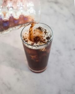 Homemade cold brew coffee in glass jar with ice cubes and coffee beans